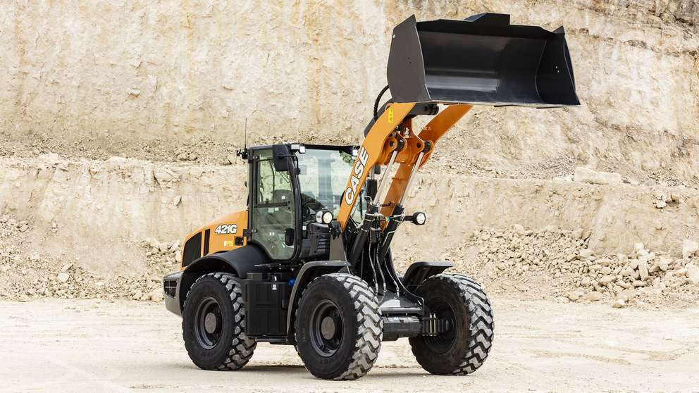 Case 421G wheel loader parked with shovel fully extended up with a mine in the background.