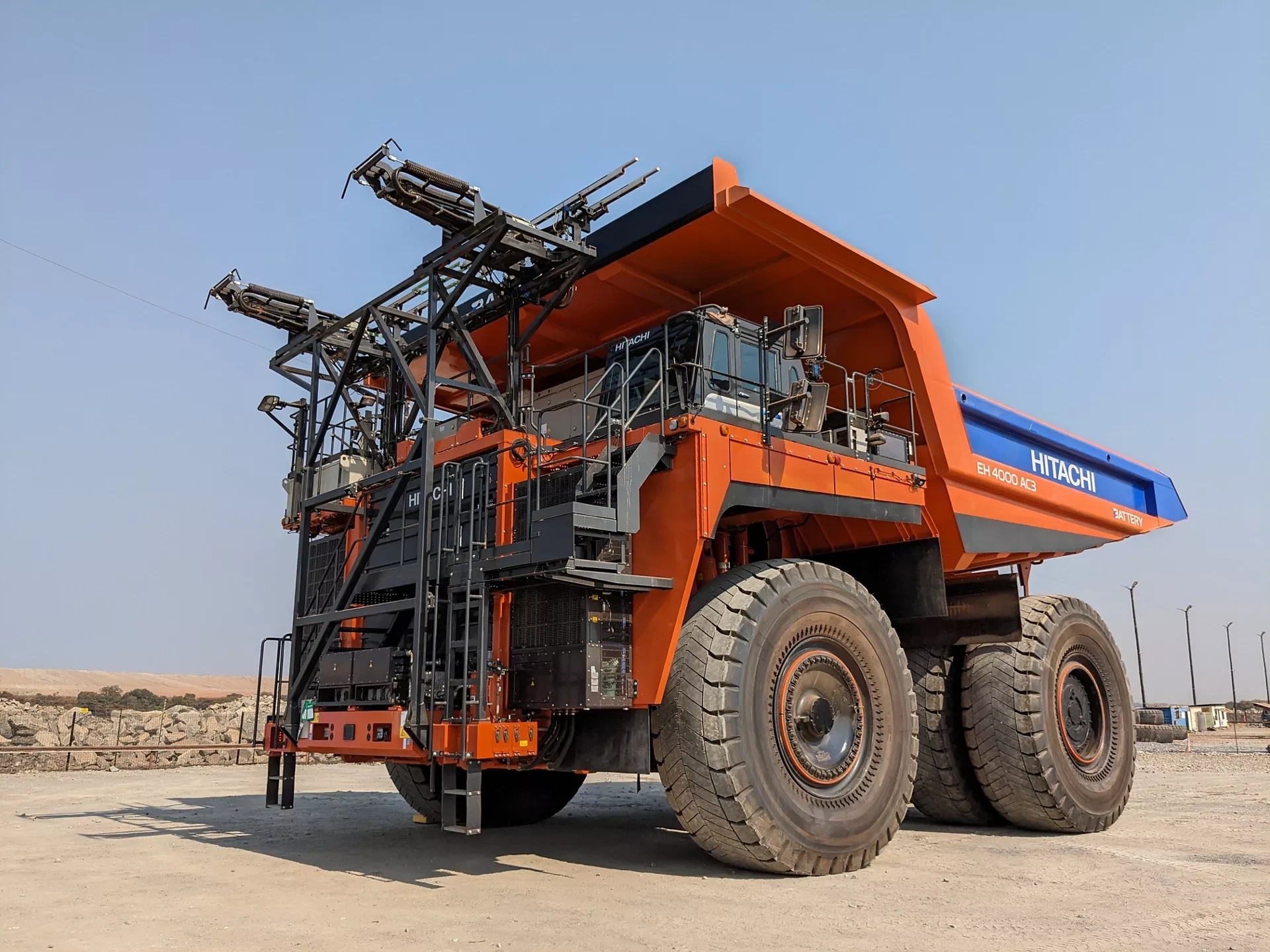 Left side view of a battery-operated orange Hitachi EH 4000 AC3 Dump Truck parked on site.