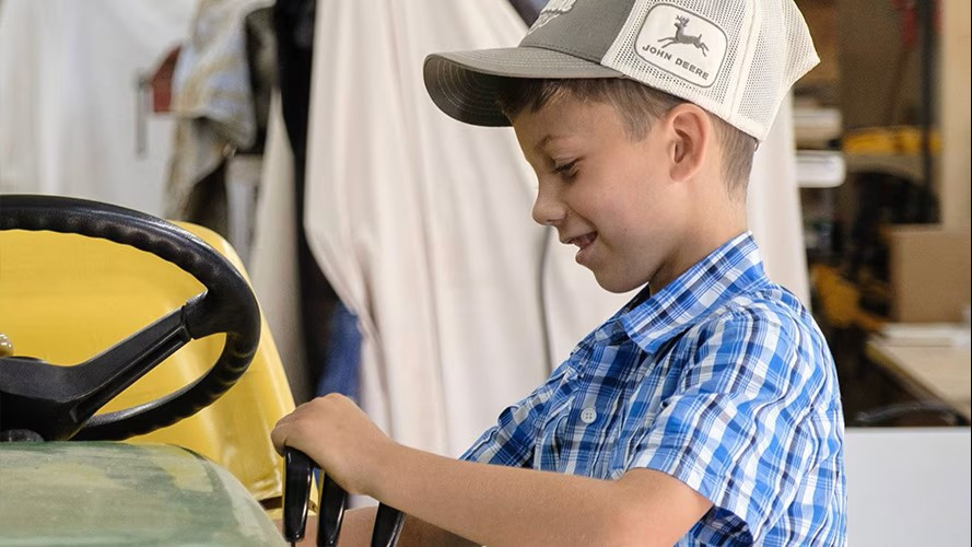 Close up of Jackson Laux the chief tractor kid for John Deere pulling levers on a tractor.