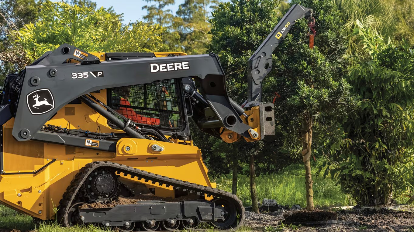 John Deere compact track loader equipped with MB60 attachment moving trees at a landscaping site