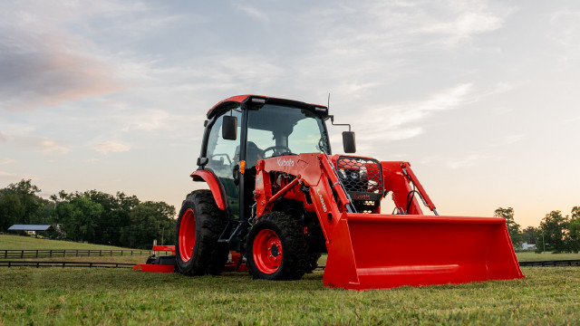 Right side view of a red Kubota Grand L70 compact tractor parked in a field.