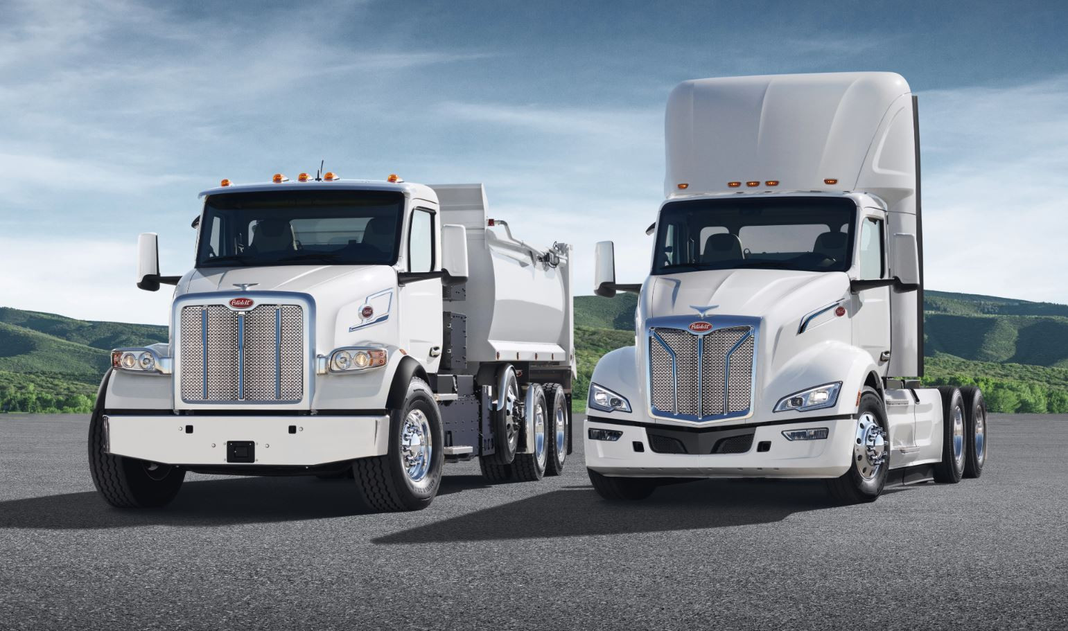 Two white Peterbilt semi-trucks in different styles parked side by side.