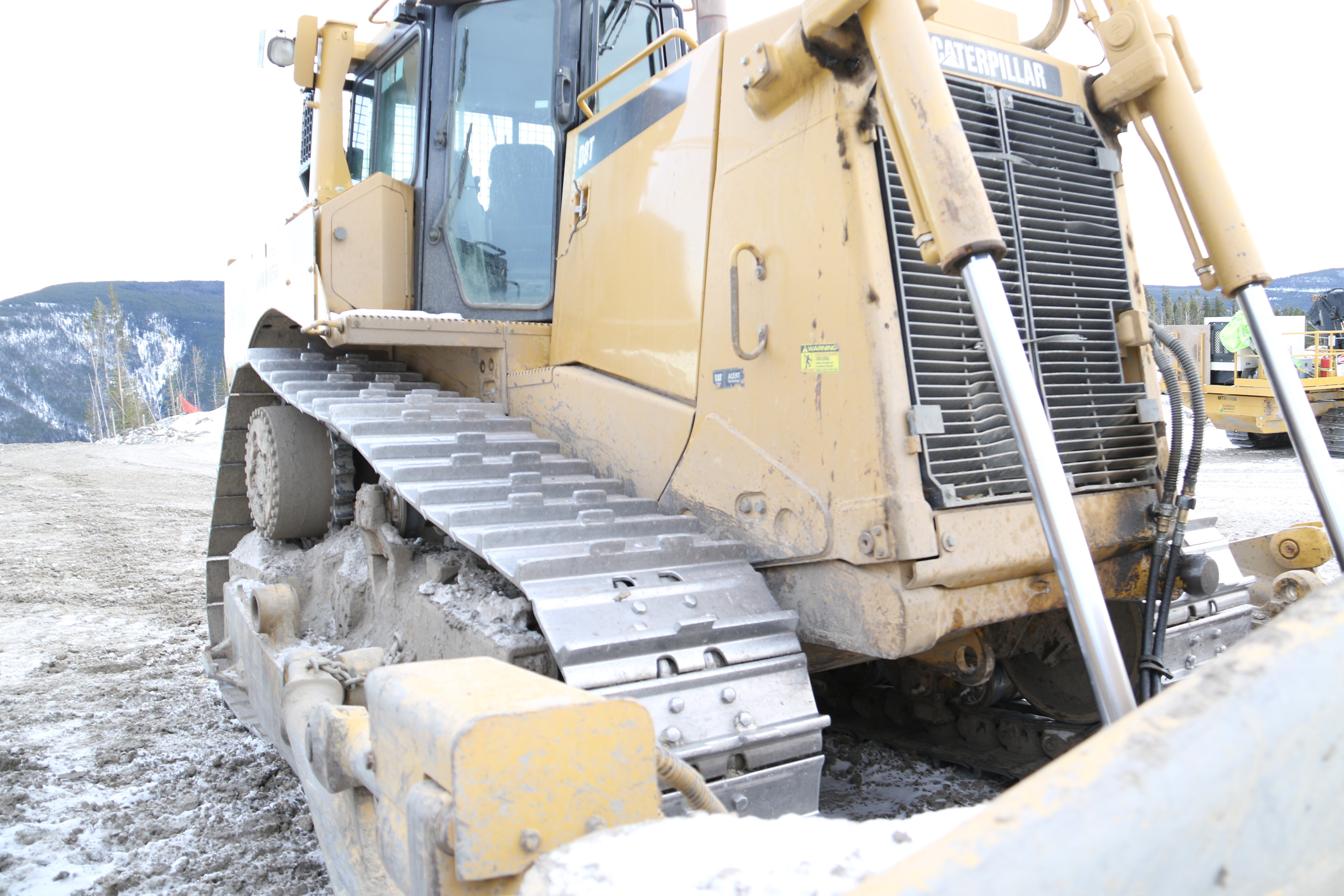 Close up partial front and side view of a Caterpillar dozer and its tracks.