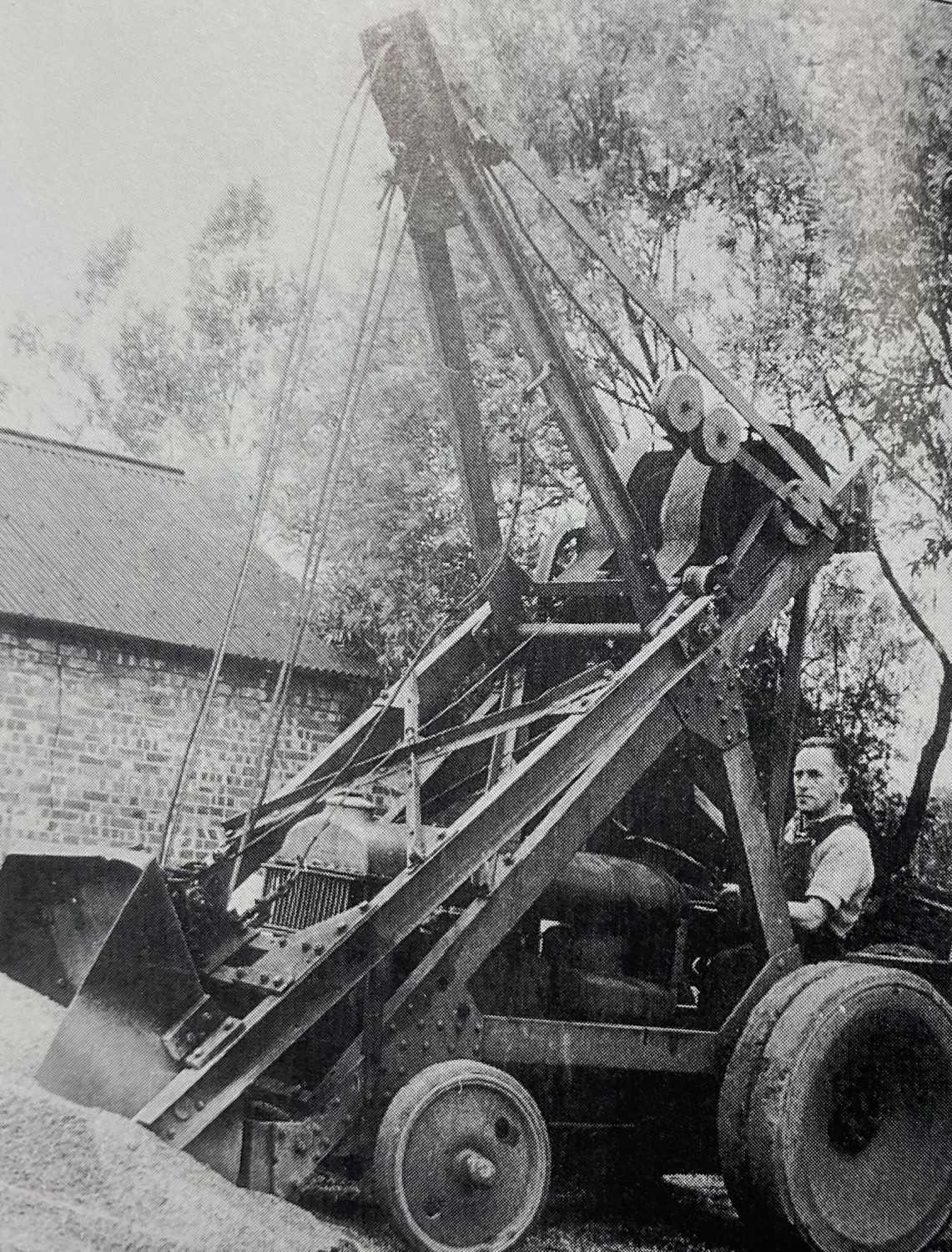 Black and white vintage wheel loader with a man standing next to it.